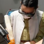 Médica com óculos de proteção aplica laser na perna da paciente em tratamento de varizes sem internação