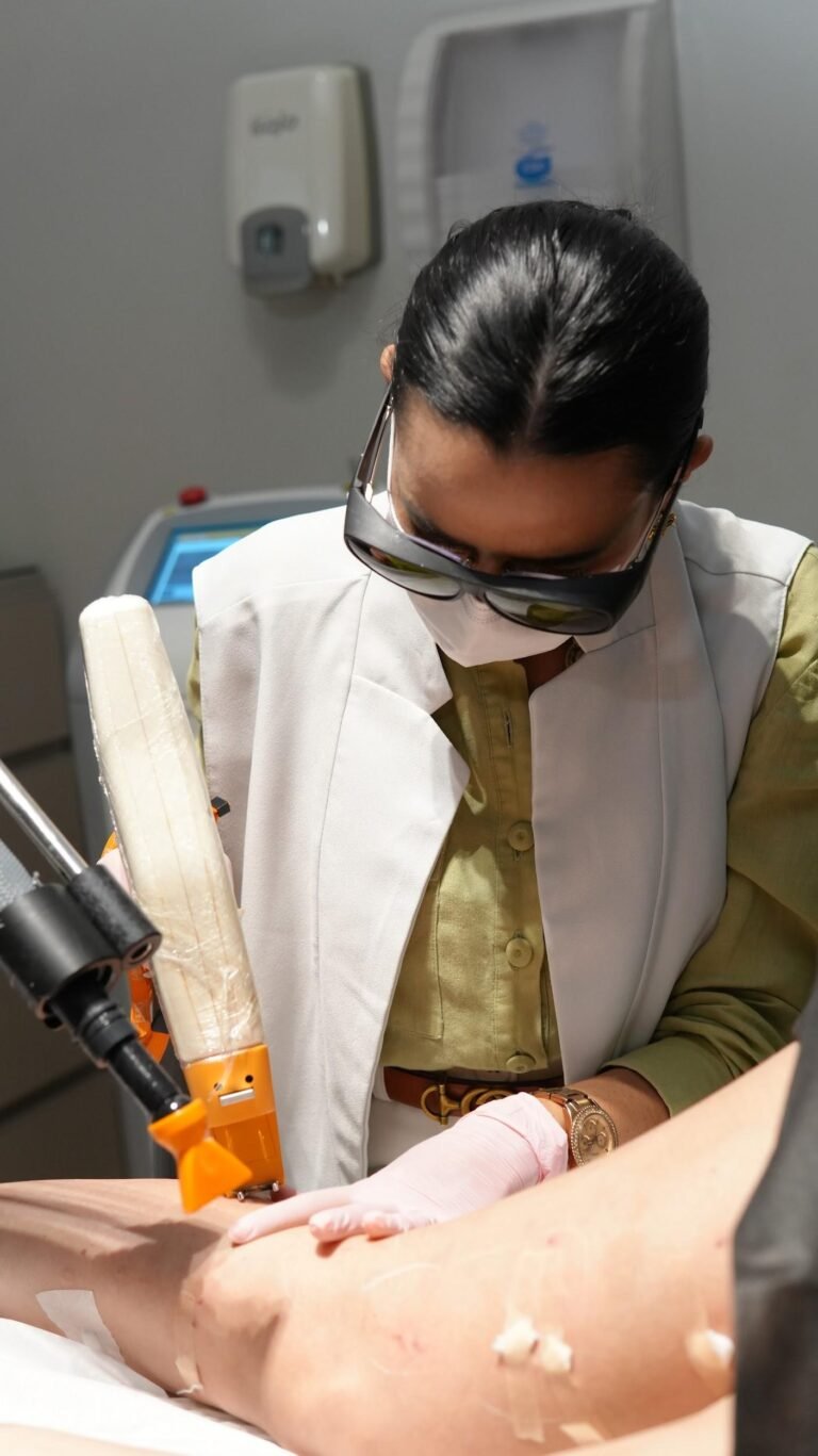 Médica com óculos de proteção aplica laser na perna da paciente em tratamento de varizes sem internação