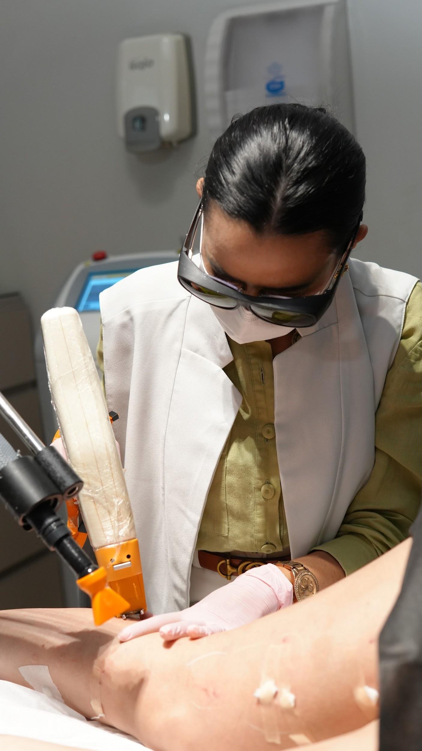 Médica com óculos de proteção aplica laser na perna da paciente em tratamento de varizes sem internação